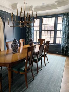 a dining room table with chairs and vases on top of it in front of a large window