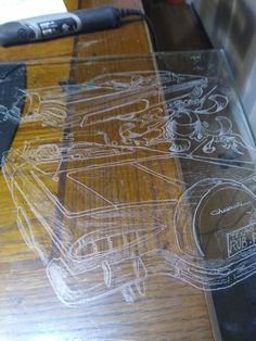 a glass table topped with a drawing of a car on top of wooden flooring