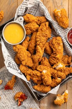 some fried food is in a basket next to a bowl of dipping sauce on a wooden table