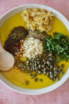 a bowl filled with different types of food on top of a pink countertop next to a wooden spoon