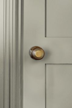 a close up of a door handle on a white door with grey paint and gold accents