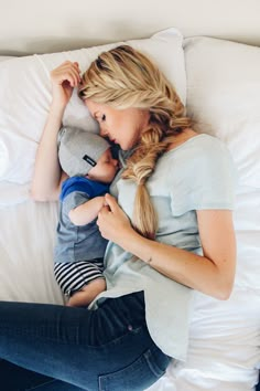 a woman laying on top of a bed holding a stuffed animal