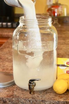 a glass jar filled with liquid sitting on top of a counter next to lemons