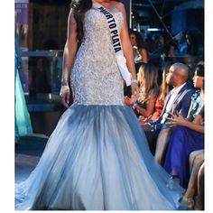 a woman in a blue and white gown walking down the runway at a fashion show