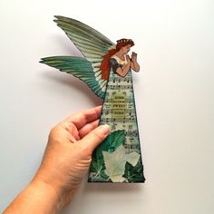 a hand holding an origami angel with musical notes on it