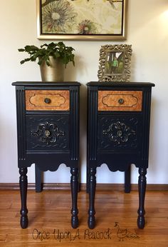 two black nightstands with wooden drawers and gold trim on the top, one has a potted plant next to it