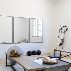 a living room filled with furniture and mirrors on the wall next to a coffee table