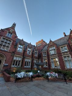 an airplane is flying in the sky over a building with many windows and plants on the ground