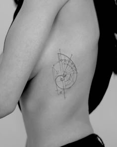 a woman with a tattoo on her back showing the shape of a circle and compass