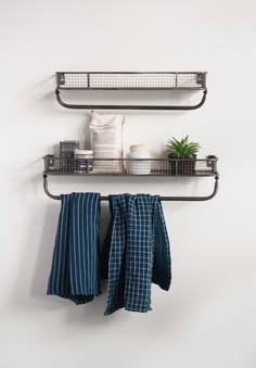 two metal shelfs with towels hanging on them and a potted plant in the corner