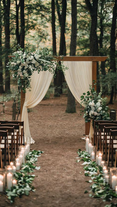 A forest wedding scene with a lace-draped wooden structure in the background with guest seating to the side of the aisleway. Candlelights and flowers create an intimate setting. Green Wedding Theme Outdoor, Country Bohemian Wedding, Diy Wedding Backyard, Bohemian Whimsical Wedding, Backyard Wedding Theme Ideas, Rustic Venue Wedding, Wedding Small Details Cute Ideas, Earthy Backyard Wedding, Wedding Ideas Forest Theme