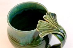 a green vase with a leaf decoration on it