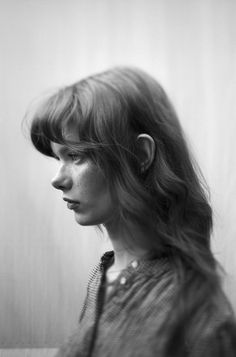 a black and white photo of a woman with hair blowing in the wind, looking to her left