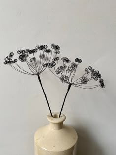 a white vase with some black flowers in it