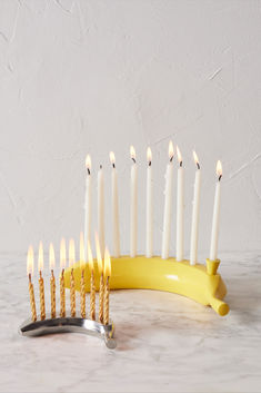 a bunch of candles that are next to a banana and some tongs on a table