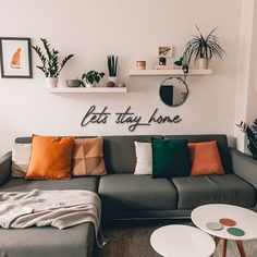 a living room filled with furniture and lots of plants on the wall above it's sofa