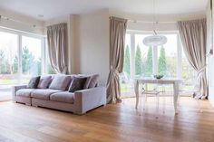 a living room filled with furniture next to a large window covered in curtains and drapes