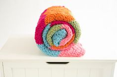 multicolored crocheted blanket sitting on top of a white shelf