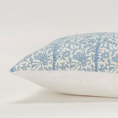 a blue and white pillow on a white surface with an embroidered design in the middle