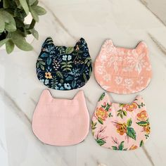 three baby bibs with flowers on them and one is pink, the other has blue