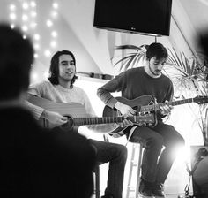 two men are playing guitars in a room