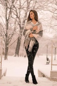 a woman is standing in the snow with her arms wrapped around her shoulders and looking at the camera