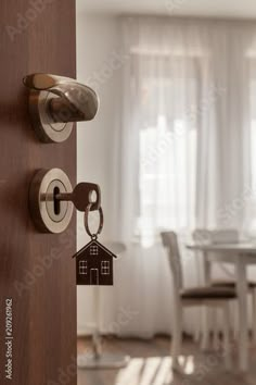 an open door with a house key hanging from it and a dining room table in the background