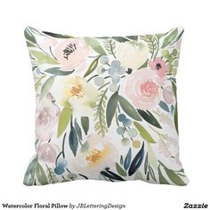 a white pillow with pink and yellow flowers on the front, and green leaves on the back