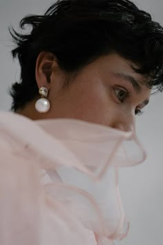 a close up of a person wearing some kind of earring with pearls on it