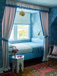 a bedroom decorated in blue and pink with a bed, chair, rug and window