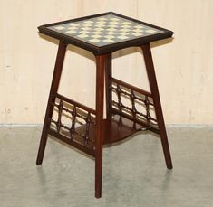 a small table with a checkered top and wooden frame on the bottom, against a beige wall