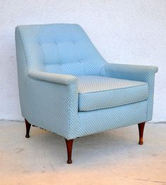 a light blue chair sitting in front of a white wall with polka dots on it