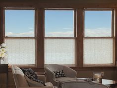 a living room filled with furniture and two windows covered in shades of white fabric covering the window