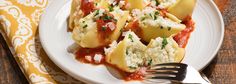 a white plate topped with ravioli covered in sauce and cheese next to a fork