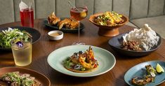 a table topped with plates and bowls filled with different types of food next to drinks