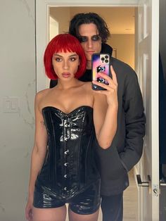 a man taking a selfie with a woman in a corset and latex