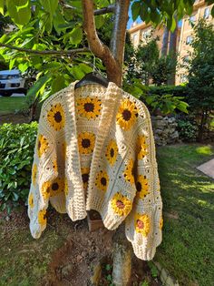 a crocheted sweater with sunflowers on it is hanging from a tree