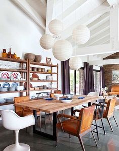 the dining room table is surrounded by chairs and shelves with plates on them, hanging from the ceiling