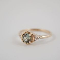 a gold ring with an aqua and white diamond in the center on a white background