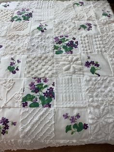 a white quilt with purple flowers on it