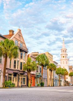 a row of buildings with palm trees in the foreground and a church steeple in the background