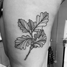 a black and white photo of a leaf on the back of a woman's thigh