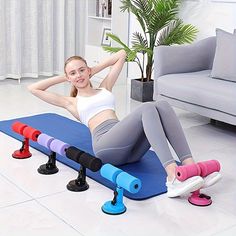 a woman laying on top of a blue mat next to two exercise rollers and a potted plant