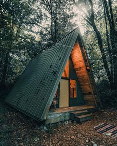 a - frame cabin in the woods with stairs leading up to it's entrance