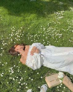 a woman laying in the grass with her head on her hand and flowers around her neck