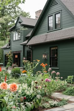 a green house with lots of flowers in the front yard