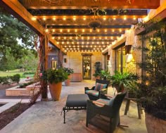 an outdoor patio covered in lights and potted plants, with seating on the side