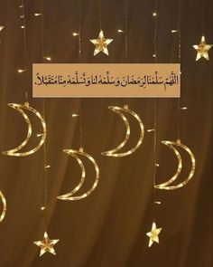 the moon and stars are hanging from strings with string lights in arabic writing on them