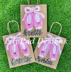 three brown bags with pink ballet shoes on them, one has the name and the other is