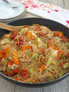 a pan filled with noodles and vegetables on top of a wooden table